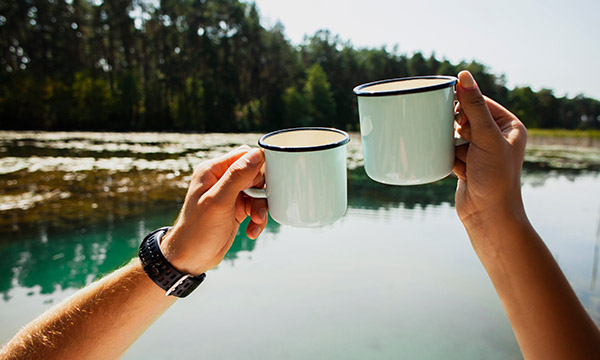 2 Kaffeetassen vor einem Meerabschnitt mit grünblauem Wasser